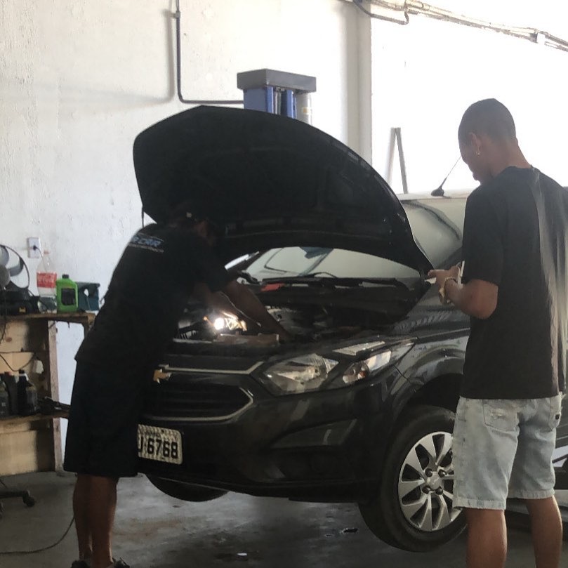 Frente de carro com o capô aberto na oficina